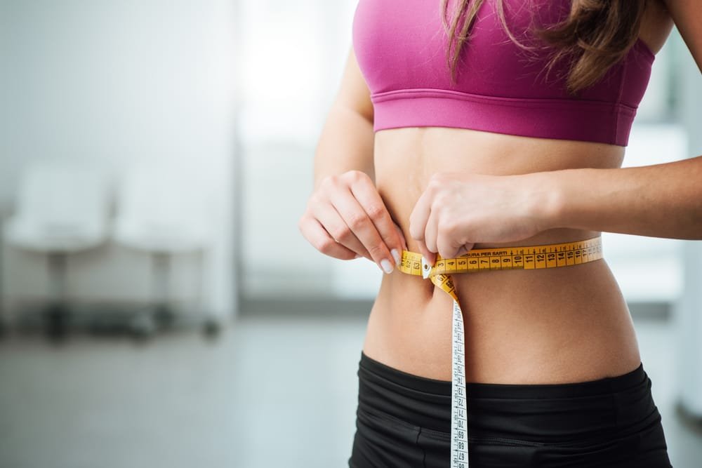 Woman measuring waist during healthy weight loss after 40 journey