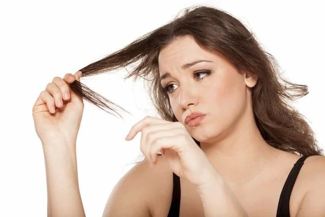 Woman checking damaged strands while learning how to take care of dry hair naturally