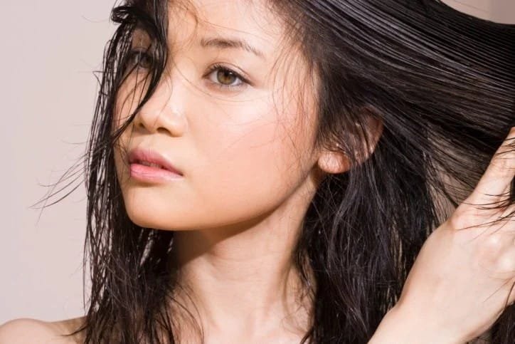 Woman with greasy hair wondering why her hair is so oily all of a sudden