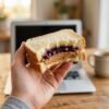 hands holding peanut butter and jelly sandwich